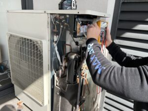 Technician repairing an air conditioning unit to restore cooling performance